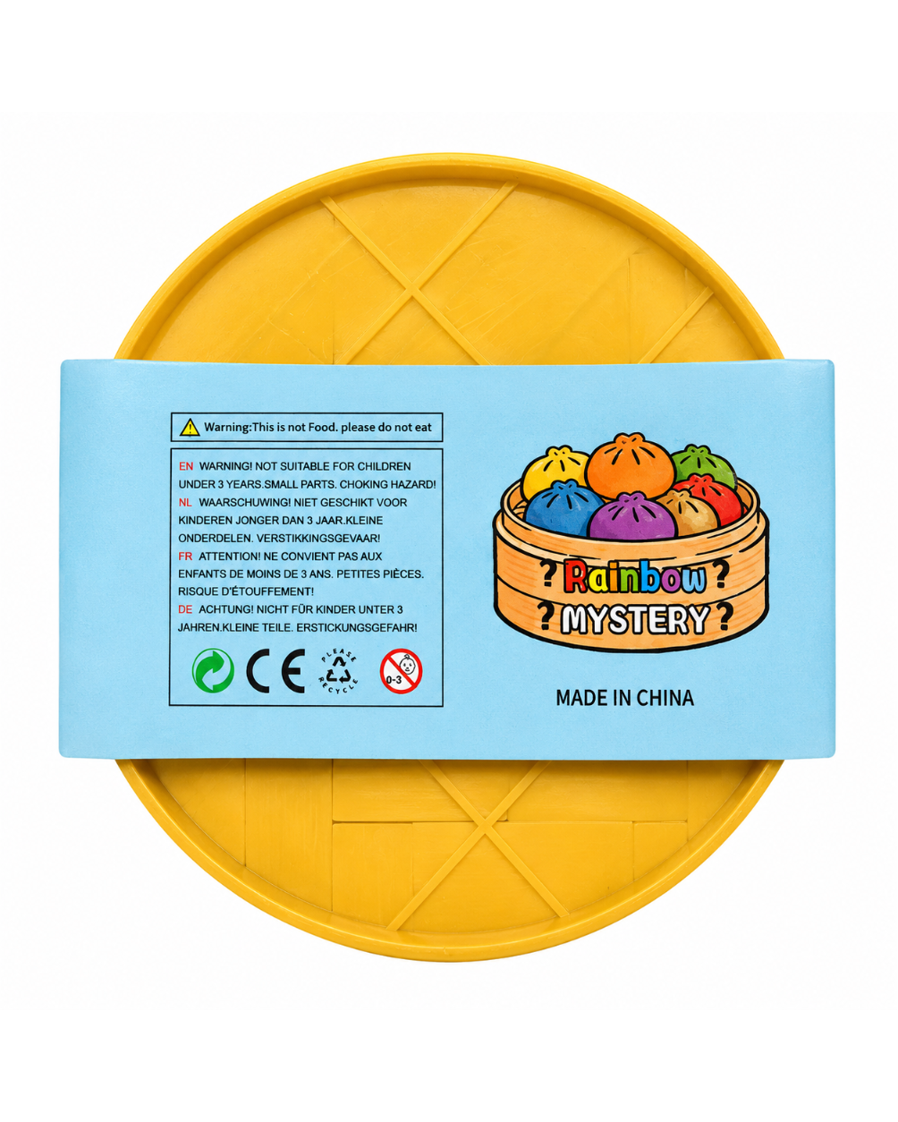 A round yellow plastic toy container with a light blue label on top, photographed against a plain white background. The label features a 'Rainbow Mystery' bun illustration and warning text.